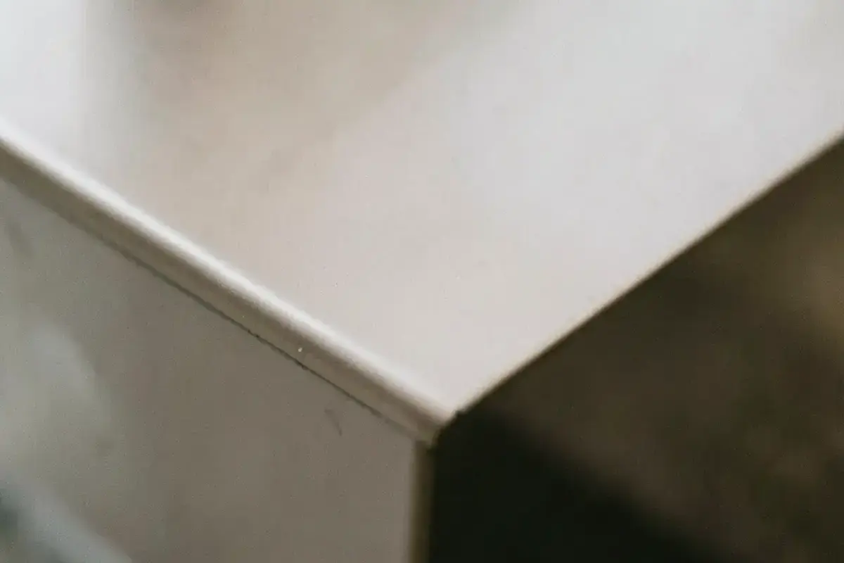 Macro closeup of a powder coated metal edge showing a smooth even satin layer with no orange peel texture