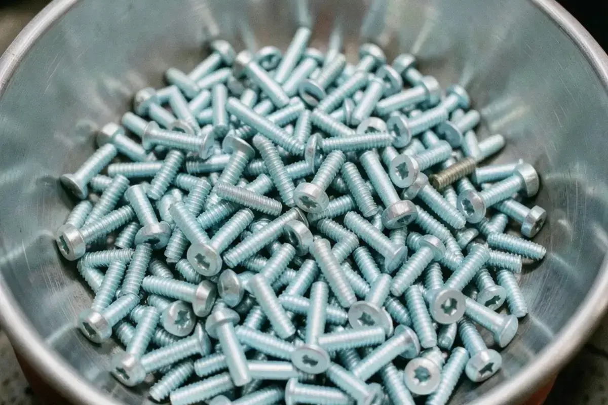 A large batch of plated steel fasteners in a vibratory finishing bowl